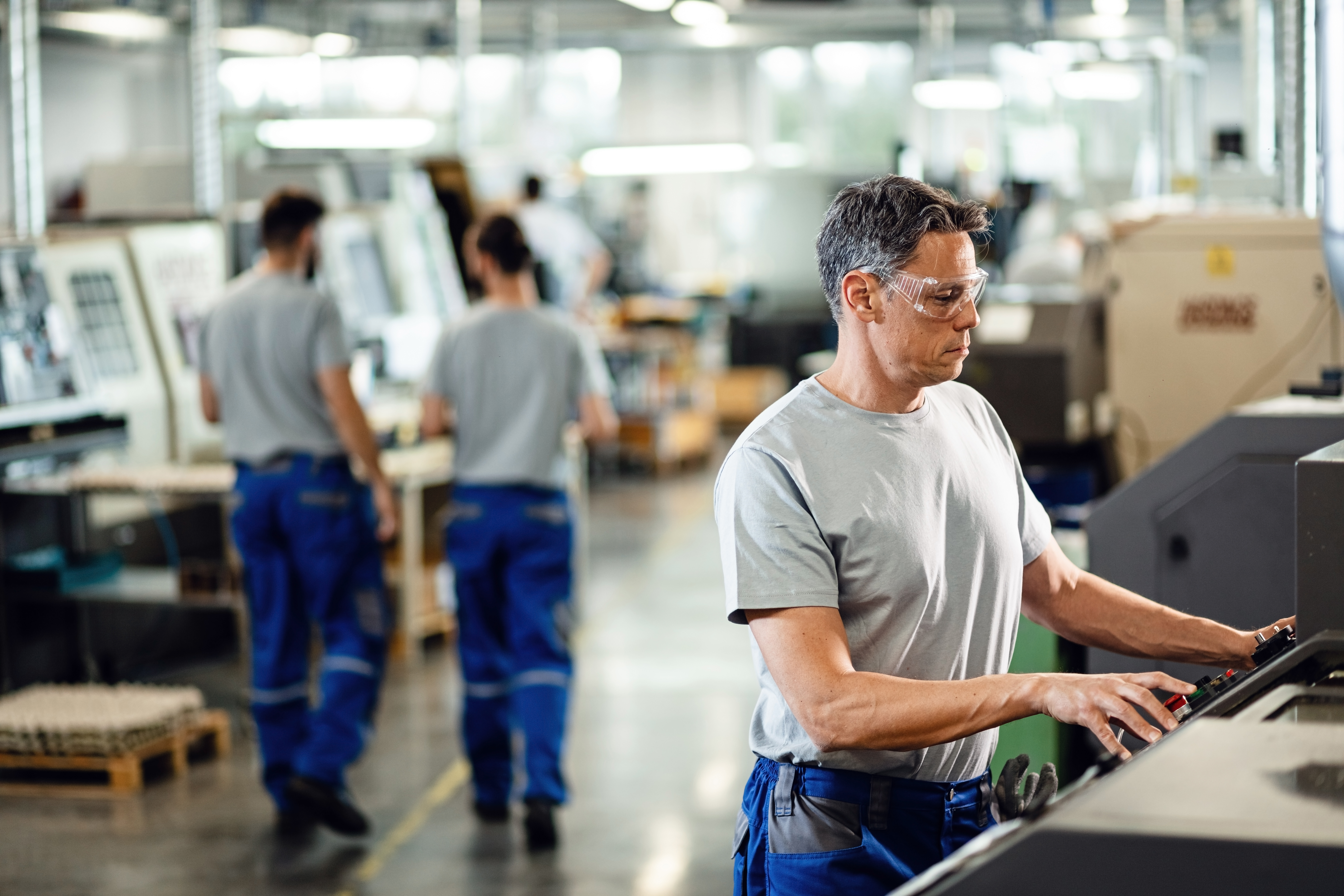 Mid Adult Worker Operating Cnc Machine While Working Industrial Facility